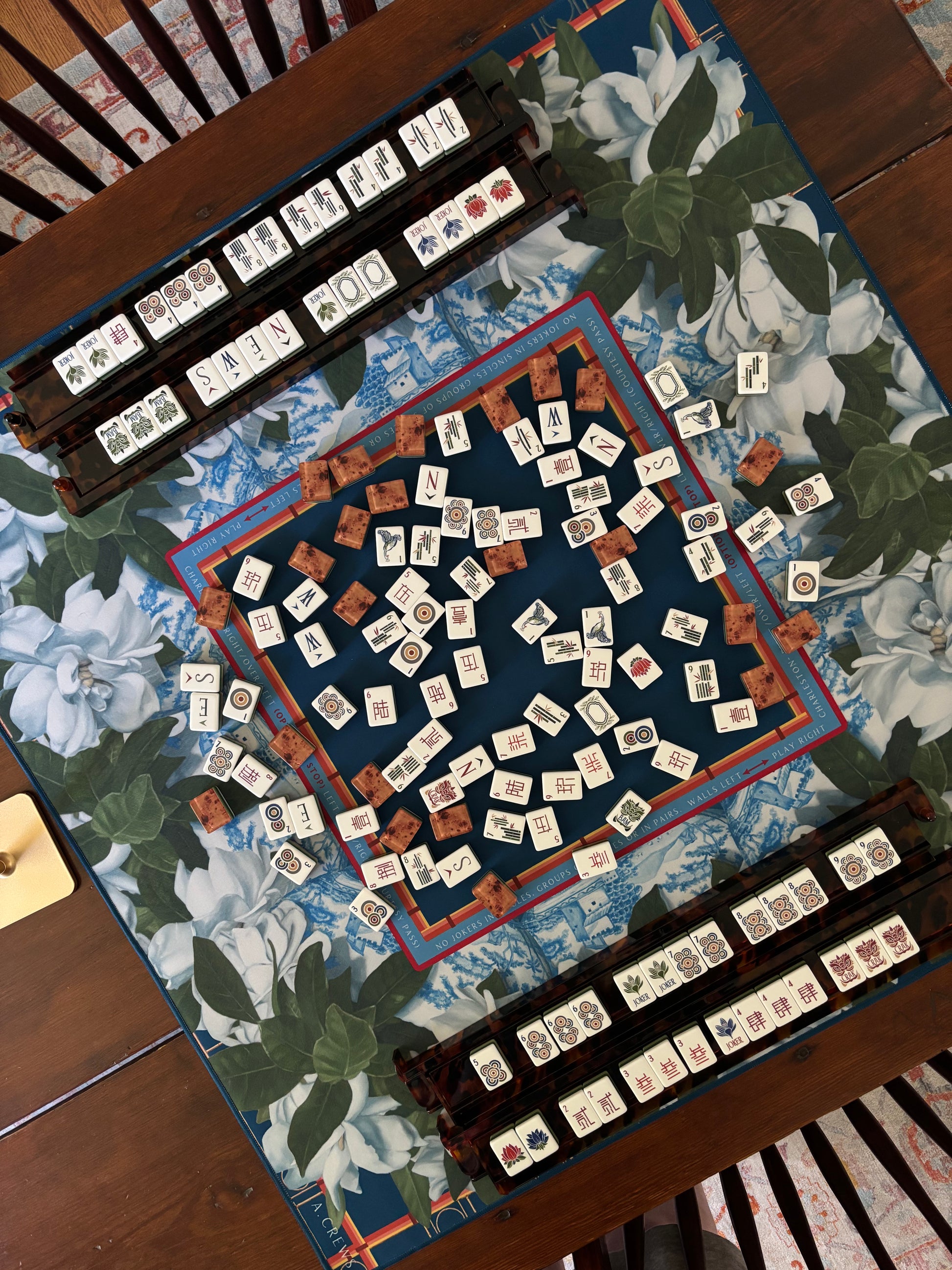 Photo of mahjong mat and tiles. Mat is by Artist Amy Crews seen here with tiles and racks by Oh My Mahjong.