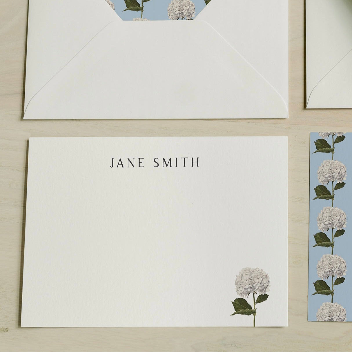 Floral Stationery set with a card and envelope featuring floral designs on a wooden surface. Art by Amy Crews